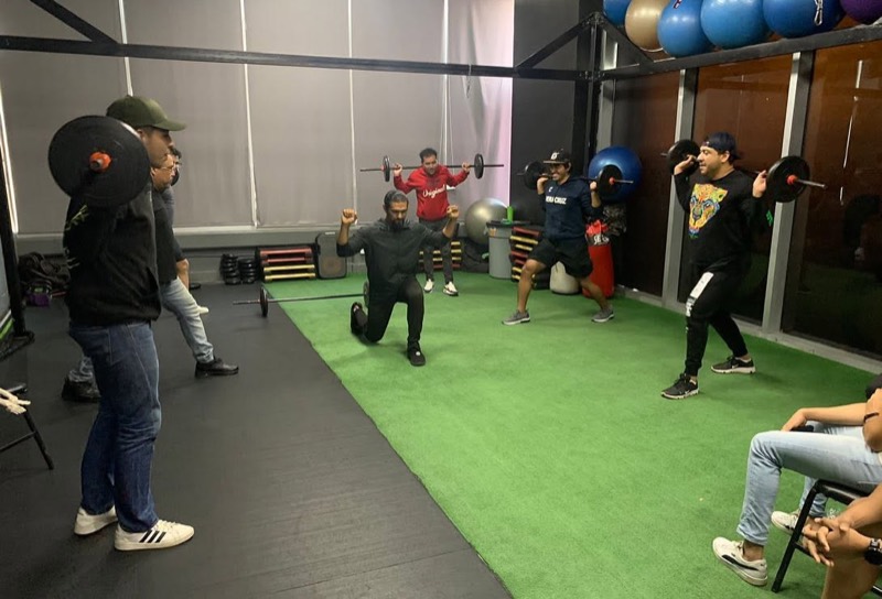 El Coach Miguel demostrando la técnica de un ejercicio frente a alumnos con barra